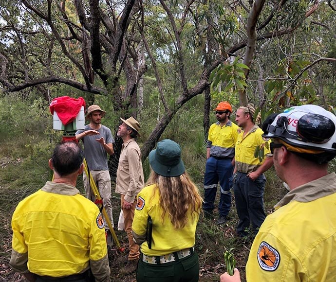 Hub researchers discussing research output with NPWS staff in the Australian bush.