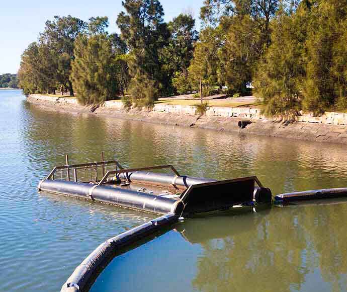 A large object floating in the river. It has an opening to catch litter.