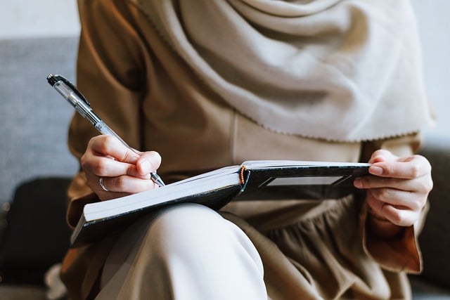 A woman holds a book and writes in it