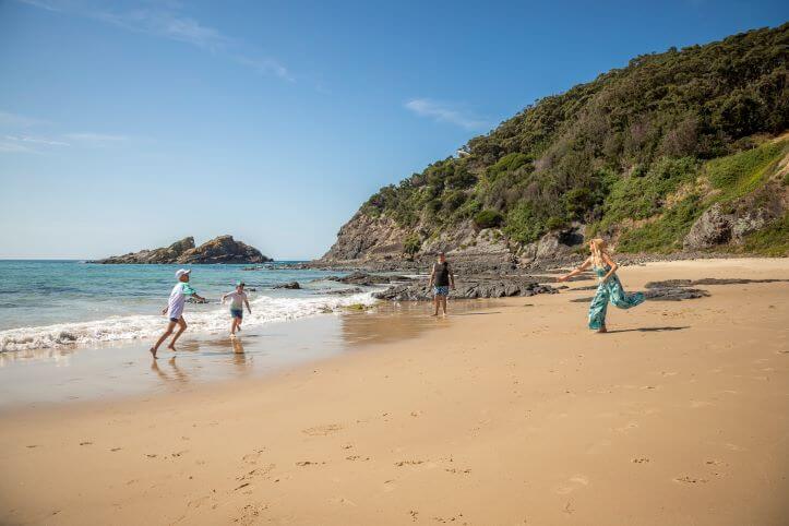 Two adults and two children playing a game of tip on the beach