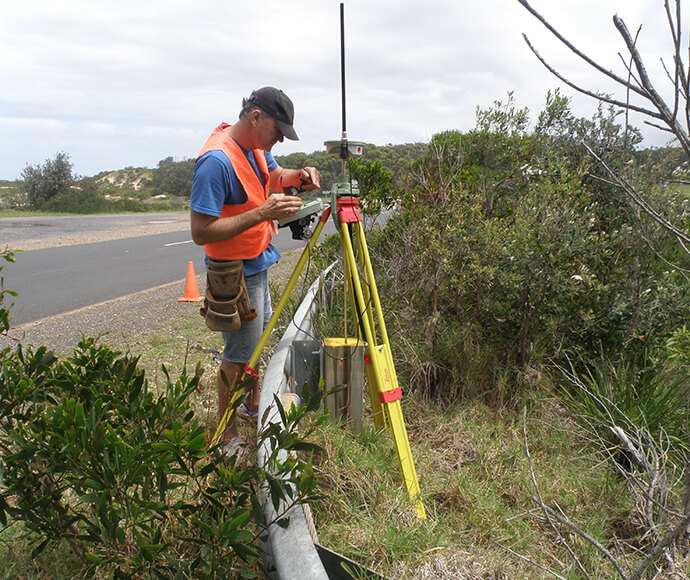 Hydrographic surveyor collecting survey mark data using a GPS smart station device, NSW south coast. 