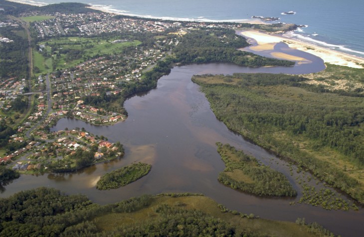 A view of Bonville Creek meeting the sea surrounded by Coffs Harbour and Bonville Beach in the distance