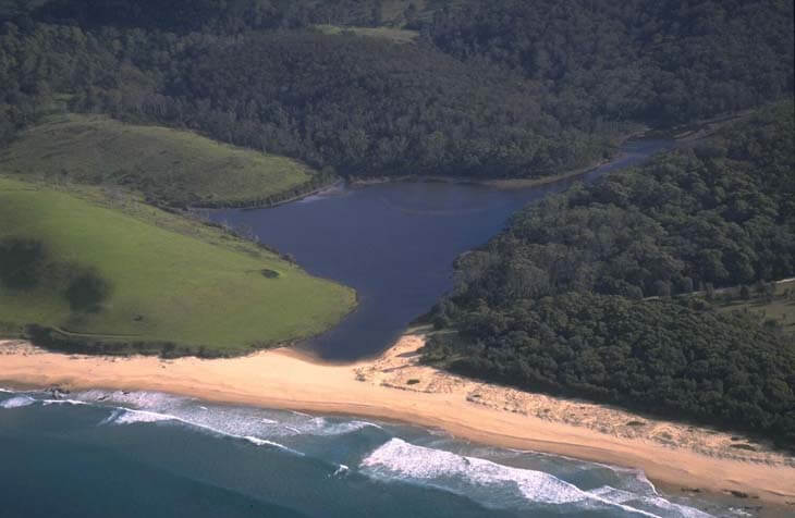 A view of Bunga Lagoon, surrounded by a tree-lined landscape and Bunga Beach in the foreground