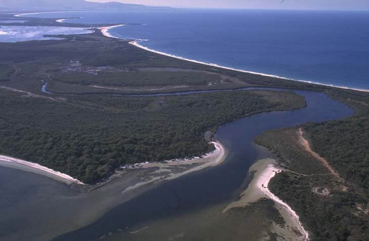 A view of Cararma Creek flowing into Jervis Bay surrounded by sand dunes with Berrys Bay in the background