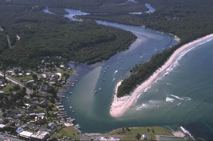 A view of Currambene Creek meeting the sea surrounded by the village of Huskisson and Callala Beach