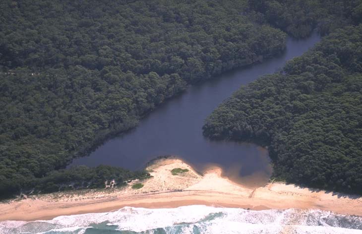 Aerial view of Nerrindillah Creek flowing into the ocean, with visible sandbanks at the river mouth..