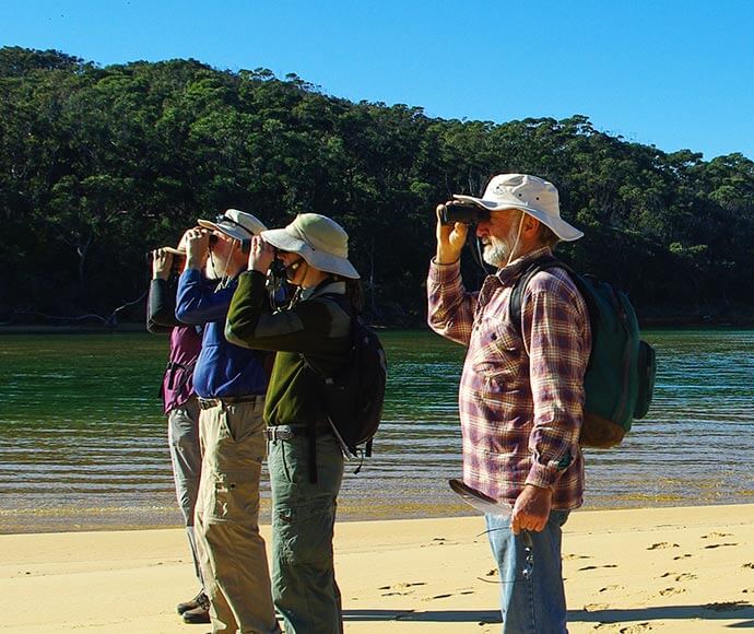 A group of people out on a walk, looking at something in the distance through binoculars