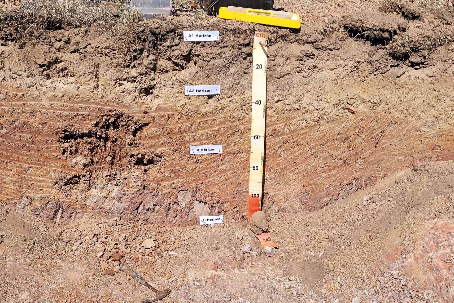 Stratigraphic section of soil layers with labeled markers and a measurement scale