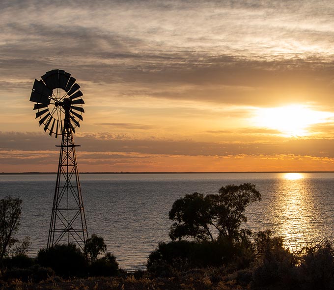 Silhouette of a windmill against a sunset over a Lake Cawndilla