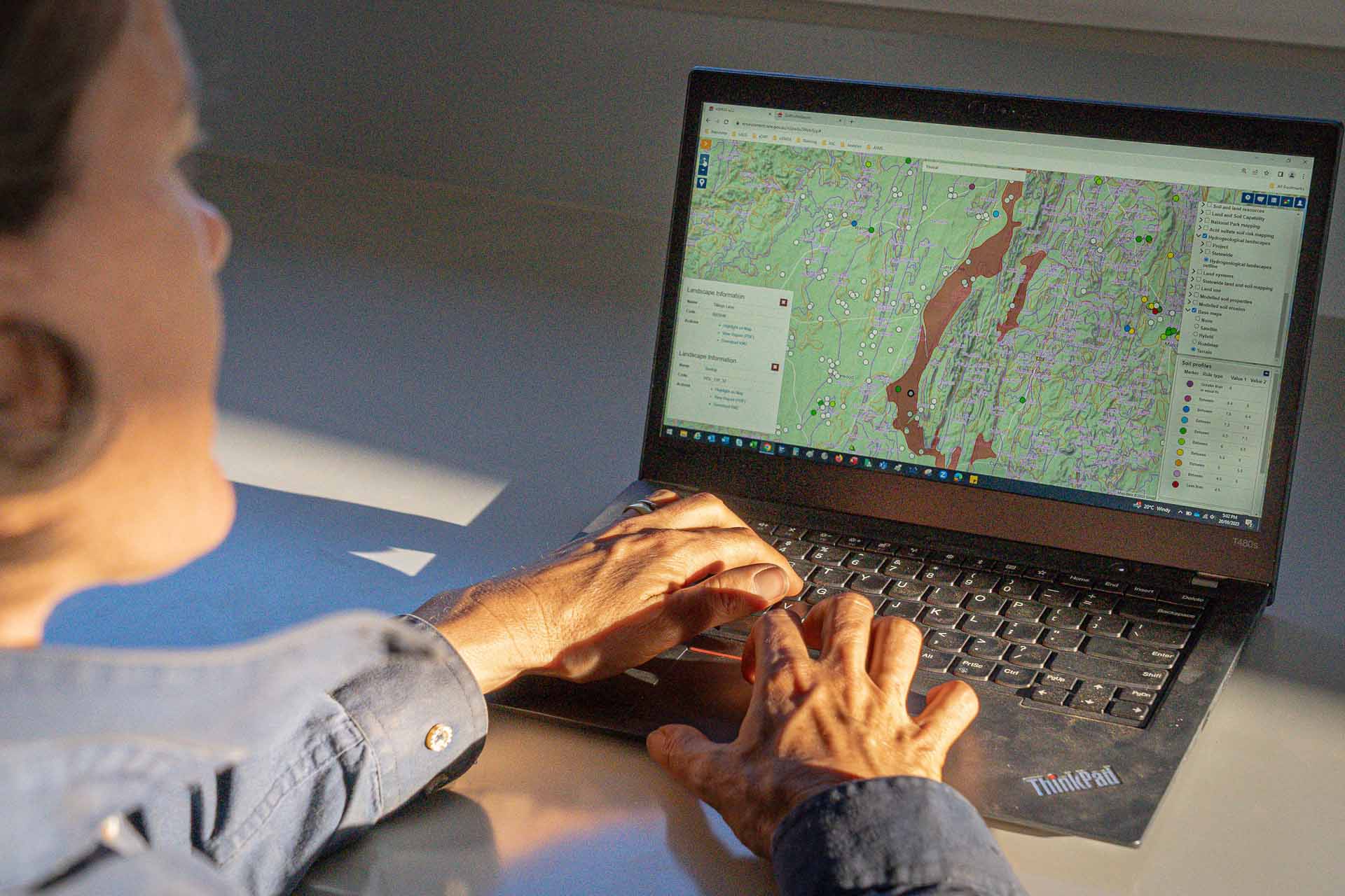 A person using a laptop displaying a map with various geographical features and locations