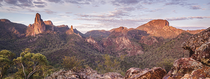 View overlooking a rocky and grassy mountain ridge. The breadknife mountain is thin and flat, and there's another mountain peak visible.