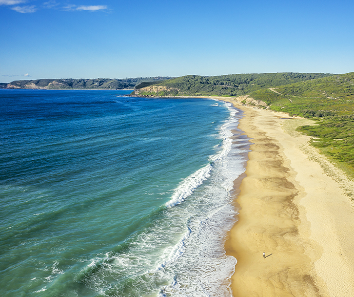 Tranquil beach with gentle waves meeting a golden sandy shore, creating a picturesque coastal landscape.