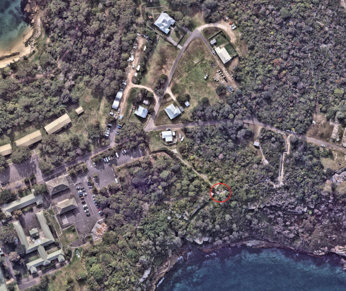 Aerial photo of strip of land with ocean inlets. Land has significant areas of tree cover and also paved, built areas.