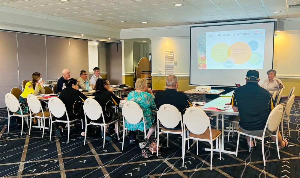 Participants seated at desks facing a screen watch a presentation about the Aboriginal joint management model.