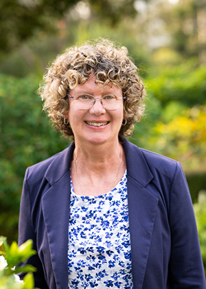 Portrait of a person wearing a blue blazer and floral top, standing outdoors