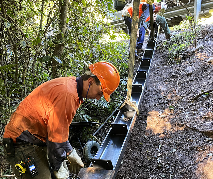 Workers offloading and moving the steel beams in a rainforest