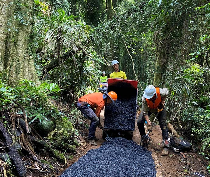 Three men shoving tar onto a path