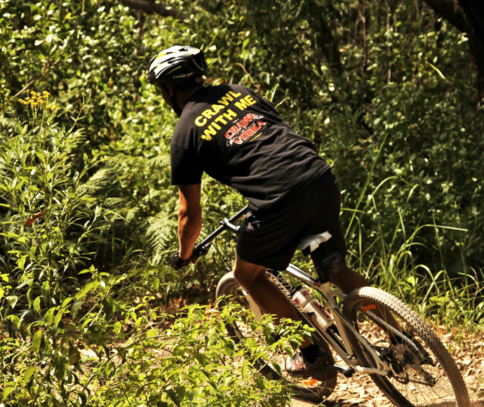 A dynamic view of mountain biking trails in Glenrock State Conservation Area, featuring a cyclist navigating a forested trail surrounded by dense greenery and natural terrain