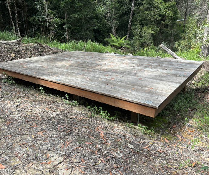 Camping platform at Yelgun Kyoomgun Camp in Nightcap National Park, surrounded by tall eucalypt trees and dense forest.