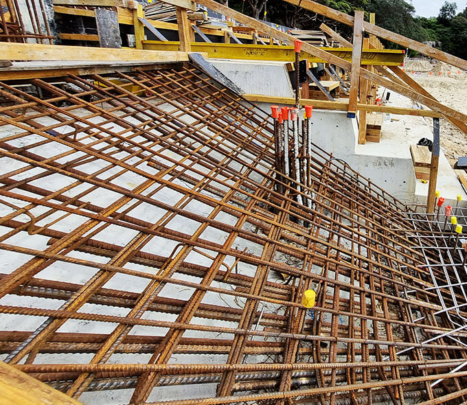 A construction site focusing on the steel reinforcement framework, indicating preparation for a concrete pour