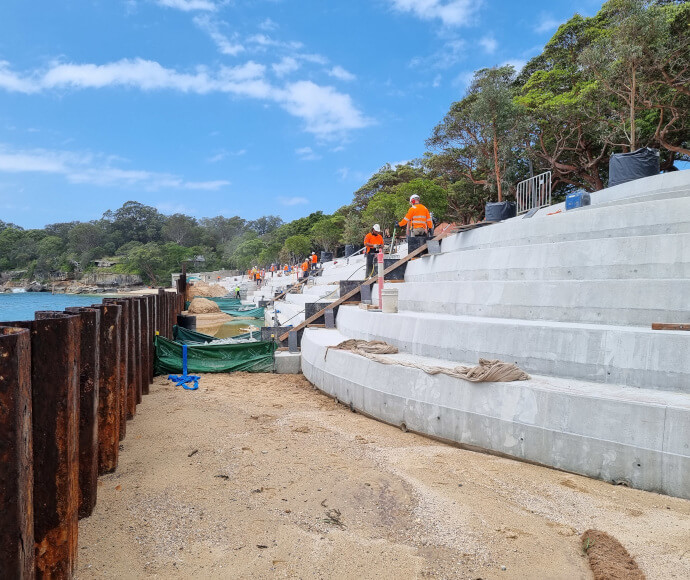 Workmen on concrete bleachers under construction in a small bay