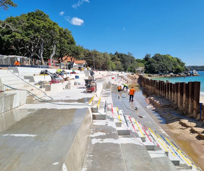 Workmen and equipment on concrete bleachers on the shore of a small bay