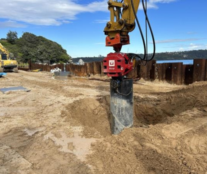 Heavy equipment sleeving defective piles in the sand at Neilsen Park seawall