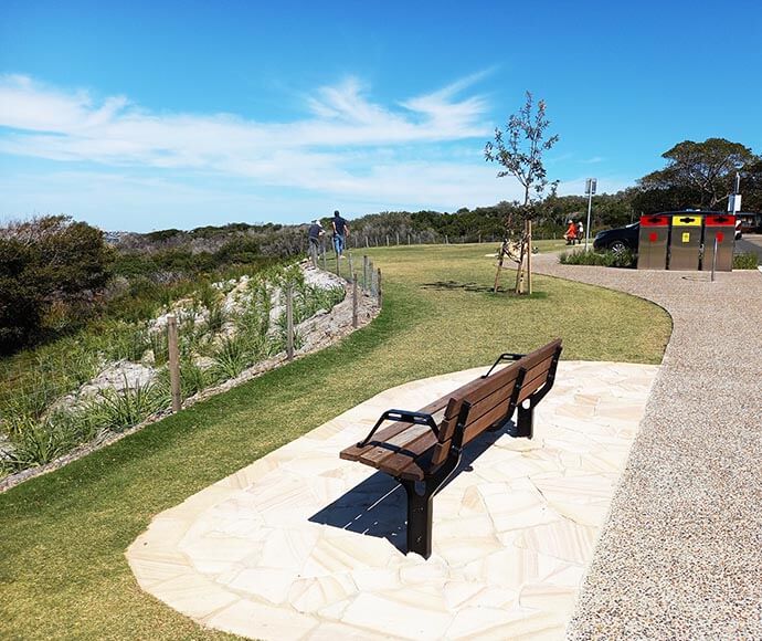 Completed landscaping at North Head, Sydney Harbour National Park, featuring a wooden bench on a paved area, surrounded by well-maintained pathways and native vegetation.