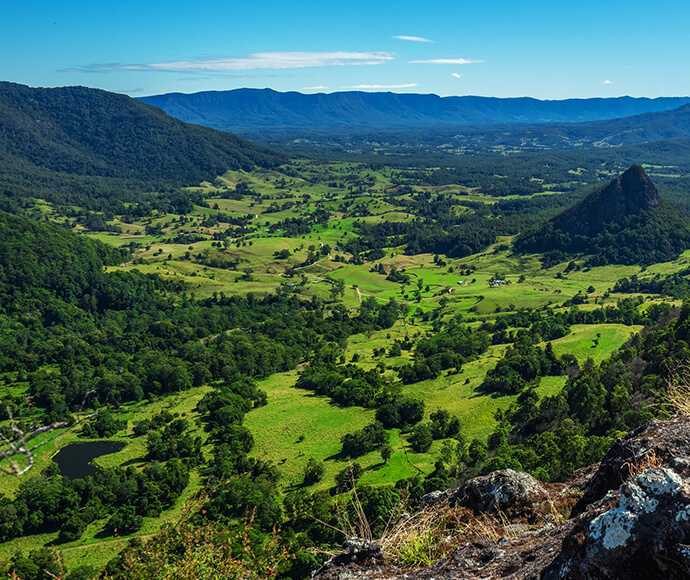 A scenic view of Wollumbin National Park, highlighting the lush, green landscape of Doon Doon under a partly cloudy sky.