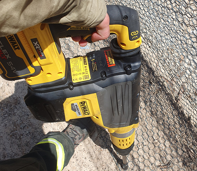 Workman using powertool to fix mesh net to ground