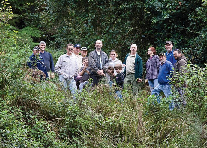 Group photo of Blue Mountains volunteers standing in the bushland surrounded by lush greenery.