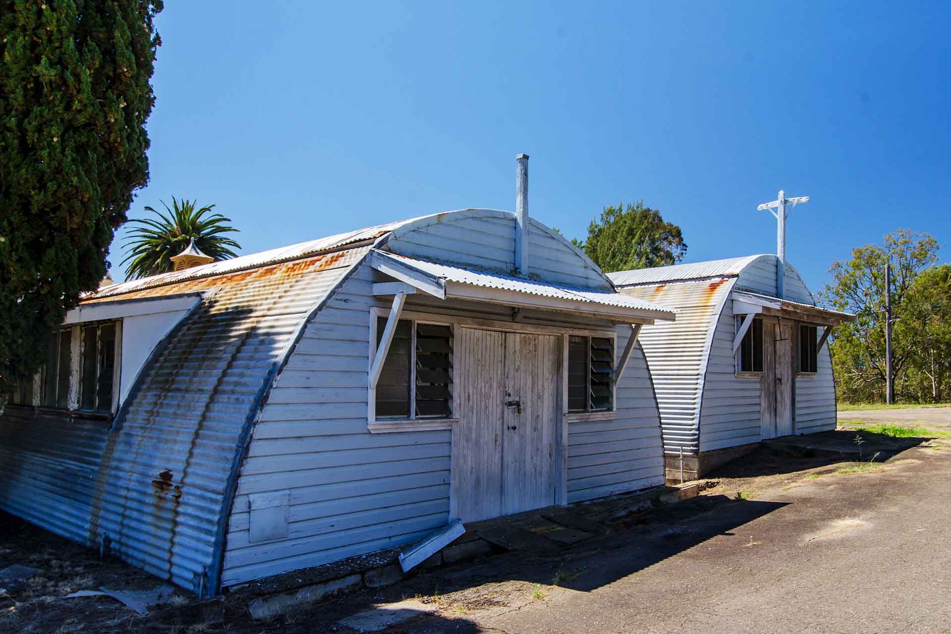 Two old Nissen huts, showing signs of age with rust and flaking paint