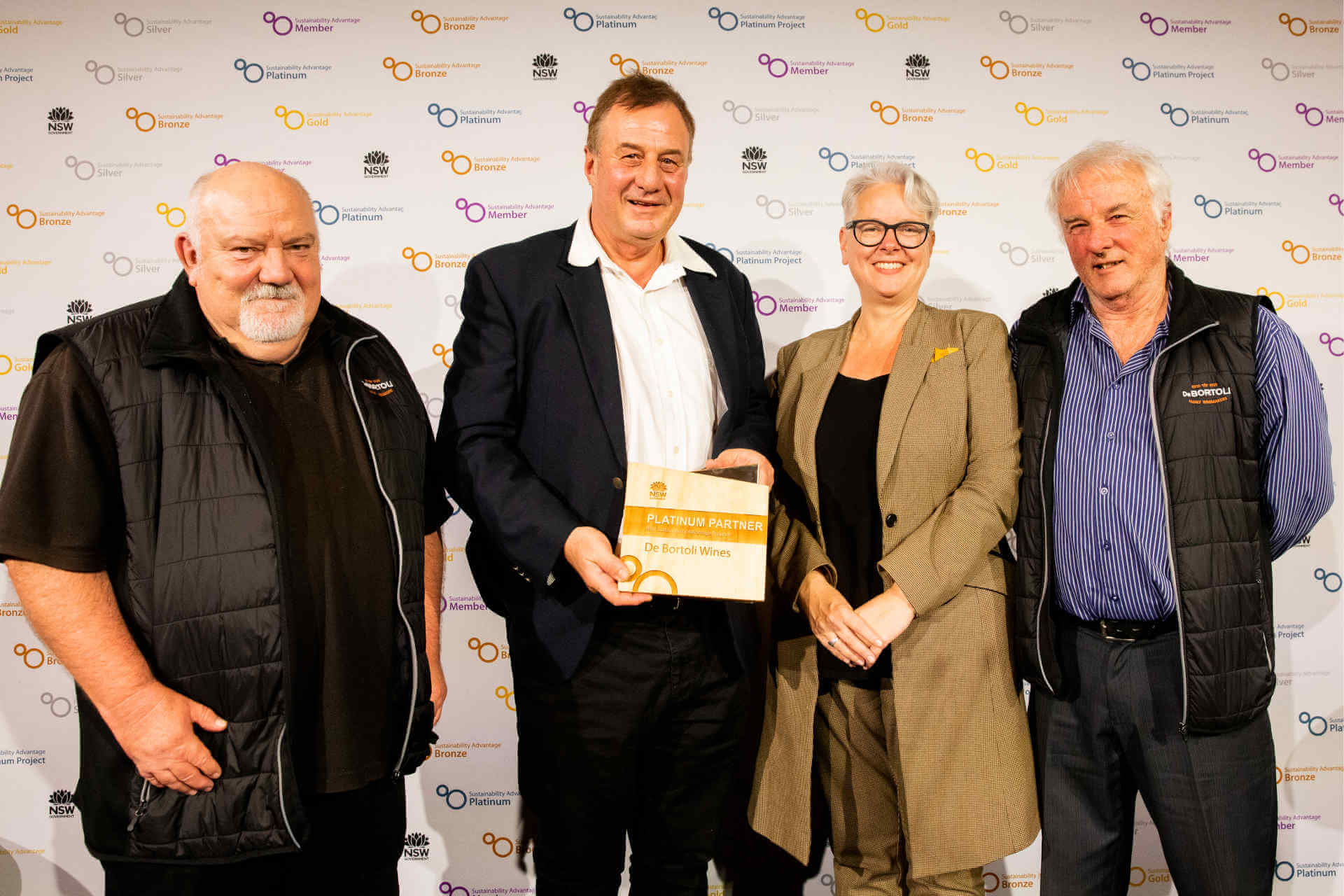 A small group of smiling people, one of whom is NSW Environment Minister Penny Sharpe, another of whom is holding a solid award