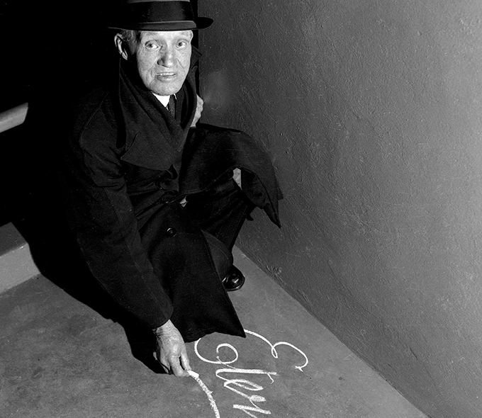 Man crorouching over a coperlate word Eternity written in chalk on the ground