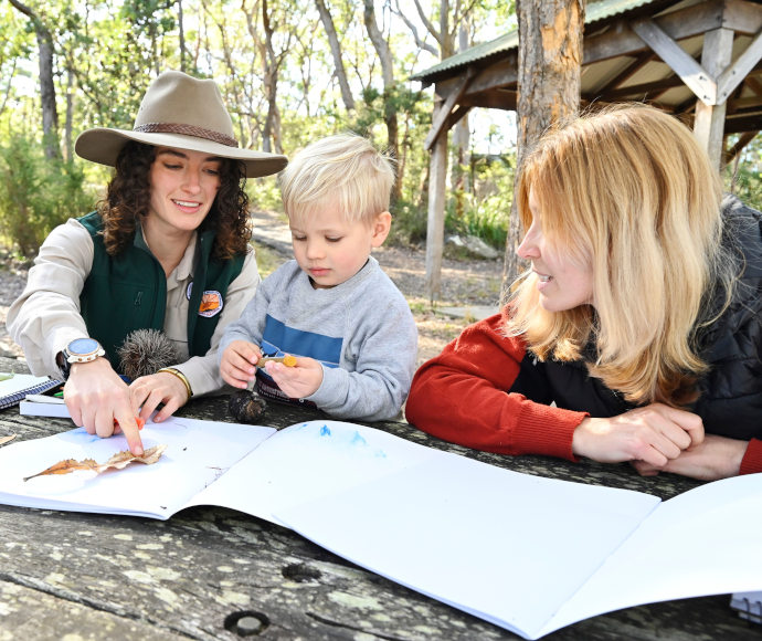 NPWS ranger showing a preschool aged child how to trace around a leaf