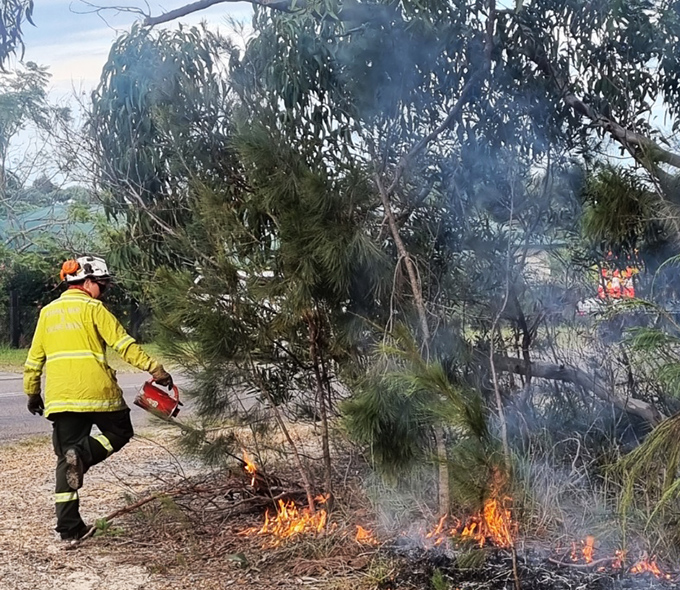 Person in hazrd gear lighting a fire