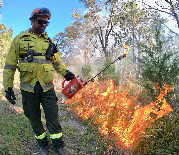 Man in protective gear engaging in controlled burn