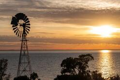 Silhouette of a windmill against a sunset over a Lake Cawndilla