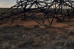 A metal transmission tower lies crumpled on the ground