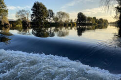 The Hunter River is a deep glassy blue colour with trees along the shore