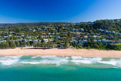 Waves breaking on a beach, houses going up the hill