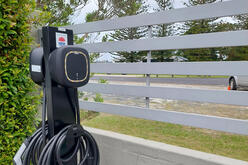 Charger on pole by white wooden fence