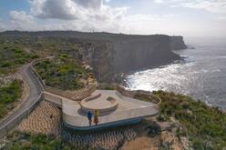 Aerial view of a couple standing at the Yiningma Lookout of Sydney Harbour National Park, offering panoramic views of the harbour and surrounding natural landscape.